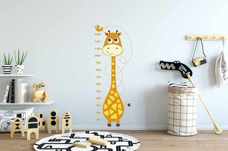 Vinil decorativo infantil con jirafa ilustrada y corazón en la cola como medidor de altura en pared blanca